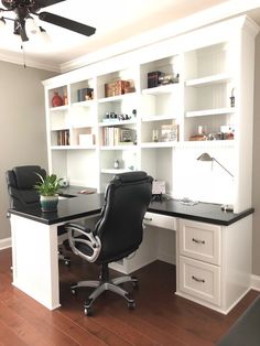 a home office with black leather chairs and white bookcases on either side of the desk