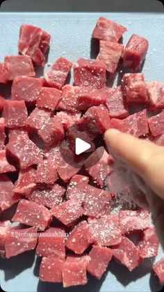 someone is cutting up cubes of raw meat