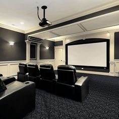 a home theater with black leather chairs and a projector screen in the middle of the room