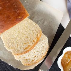 a loaf of bread sitting on top of a cutting board next to a bowl of jelly