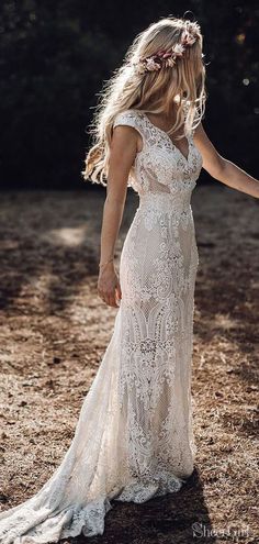 a woman in a white wedding dress holding her hand out to the side with trees in the background