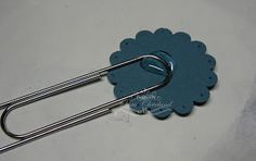 a blue paperclip with a metal holder attached to the handle on a white surface