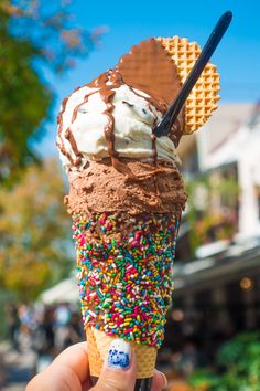 an ice cream cone with chocolate and sprinkles on top, in front of a building