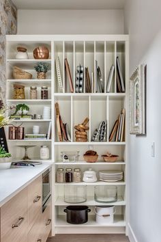 a kitchen with white shelves filled with dishes and cooking utensils