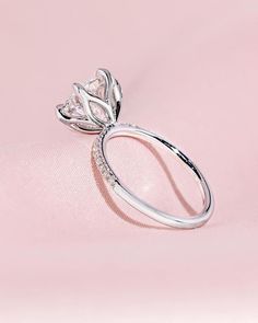 a diamond ring sitting on top of a pink surface