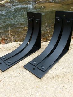 pair of black metal bookends sitting on sand next to water