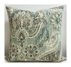 a blue and white pillow with an ornate design on it's side, sitting on a table