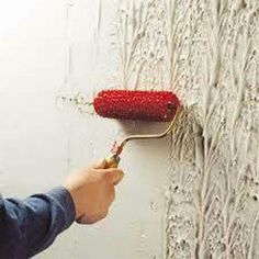 a person painting a wall with white paint and a red roller on it's side