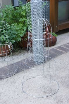 two metal planters sitting next to each other in front of a building with plants growing out of them