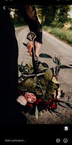 a person holding a guitar on the side of a road with flowers in front of them