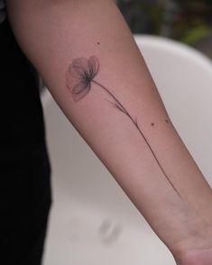 a woman's arm with a single flower tattoo on the left side of her arm