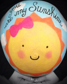 a person holding up a painted rock with the words you are my sunshine on it