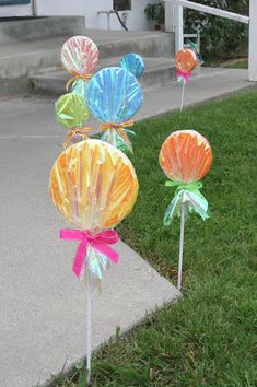 some colorful candy lollipops sitting in the grass on top of a sidewalk