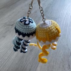 two crocheted items hanging from chains on a table