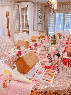 a table with gingerbread houses and candy cups