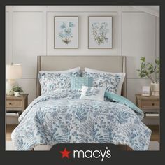 a bed with blue and white comforter in a bedroom next to two pictures on the wall