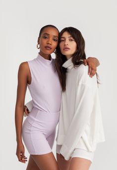 two women in bodysuits posing for the camera with their arms around each other