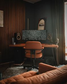 a brown leather chair sitting in front of a desk with speakers on top of it