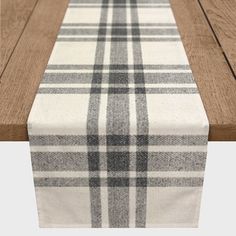 a plaid table runner on top of a wooden table with white and black stripes down the middle