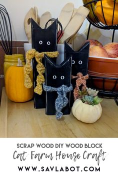 several black cats made out of wood sitting on top of a table next to pumpkins