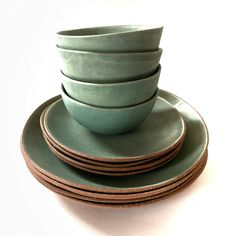 a stack of green dishes sitting next to each other on top of a white table