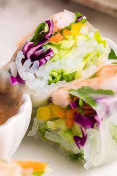 a white plate topped with lots of veggies next to a bowl of dipping sauce