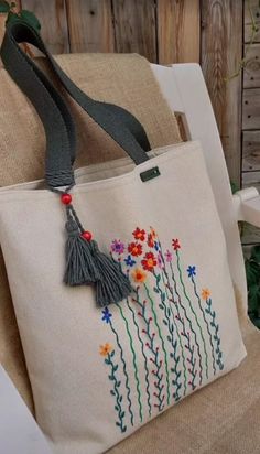 a handbag with flowers and tassels on it sitting on a chair in front of a wooden wall