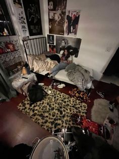 a bedroom with lots of stuff on the floor and people sleeping in bed next to each other