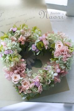 a wreath with pink and green flowers sitting on top of a piece of paper