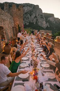 a group of people sitting at a long table with plates and drinks in front of them