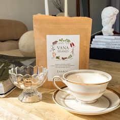 there is a tea cup and saucer on the table next to a bag of tea