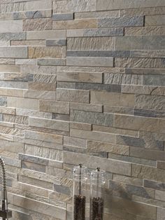 a kitchen counter top with a sink and faucet in front of a stone wall