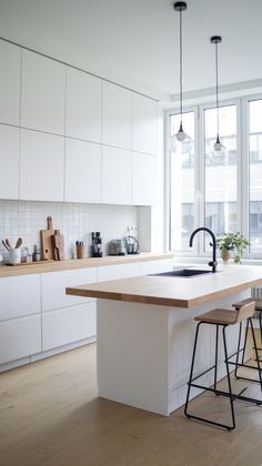 a kitchen with white cabinets and counter tops next to two stools in front of a window