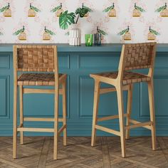 two wooden chairs sitting next to each other in front of a blue bar with wallpaper