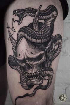 a man's thigh with a snake on it and a skull in the middle