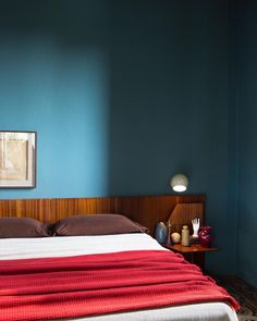 a bedroom with blue walls and a red blanket on the bed