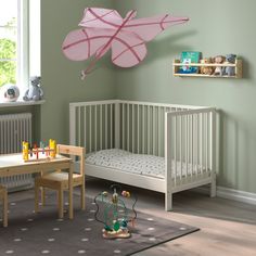 a child's room with green walls and white furniture, including a pink umbrella