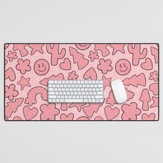 a pink mouse pad with hearts and smiley faces on it, next to a keyboard