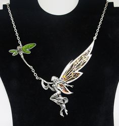 This stunning Gothic necklace was made by the highly sort after Alchemy and depicts 'The Fairy's Dream', it was made from the best quality English Pewter.   The necklace has a beautifully crafted fairy with open copper fretwork wings, she is accompanied by a green enamel winged dragonfly. The necklace is stamped Alchemy UK, Made in England. Measurements:   Pendant  size - 14.5cm 10cm. Necklace length - 55cm. Silver Fairy Necklace, Fairy Pendant Jewelry Gift, Fairy Pendant Necklace, Fairy Charm Necklace, Elegant Silver Wing-shaped Necklace, Gothic Necklace, Vintage Gothic, Green Enamel, Wedding Jewellery Necklace