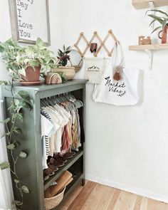 a green shelf filled with lots of clothes next to a wall mounted potted plant