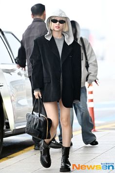 a woman in black coat and boots walking down the street