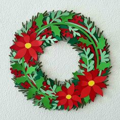 a paper wreath with red flowers and green leaves