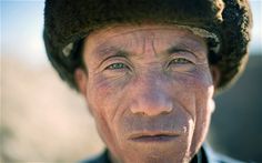 an old man wearing a hat and looking at the camera