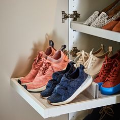 several pairs of shoes are on display in a shoe rack with white shelving behind them