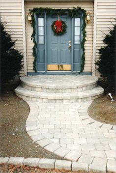 a blue front door with wreaths on it and steps leading up to the entrance