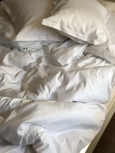 an unmade bed with white sheets and pillows on it's bottom half is shown