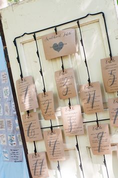 an old door is decorated with wedding seating signs and paper tags that spell out the names of their guests