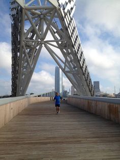 a man running across a wooden bridge with tall buildings in the background