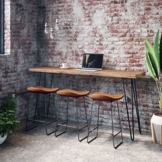 three stools sit in front of a table with a laptop on it and a potted plant next to it