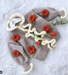 a knitted sweater with flowers on it laying on a white furnishing area